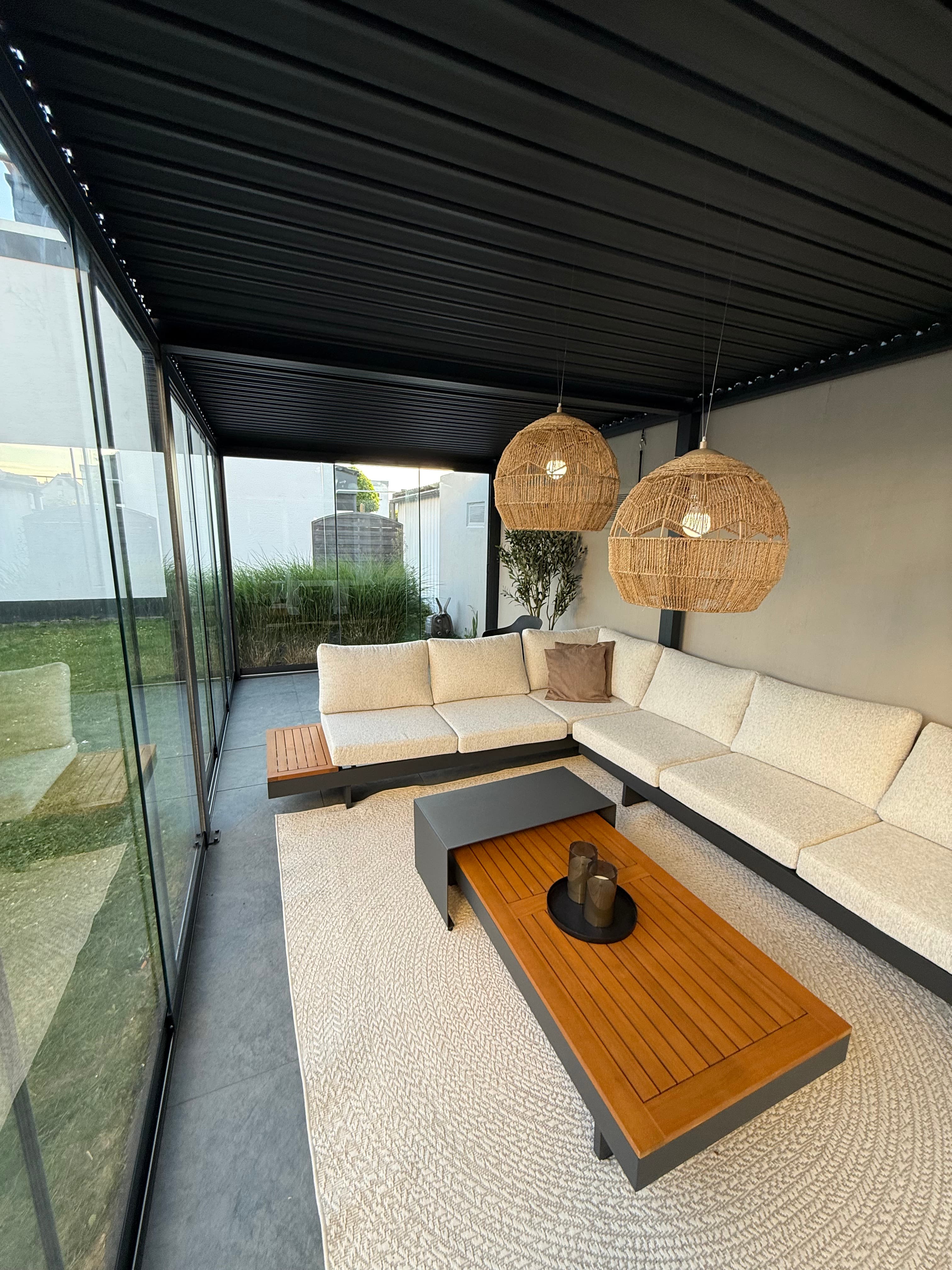 Loungehoek onder een lamellendak met glazen schuifwand
